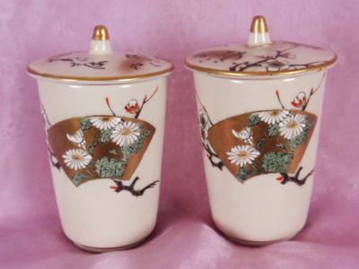 two matching cups with lids, one lid is repaired